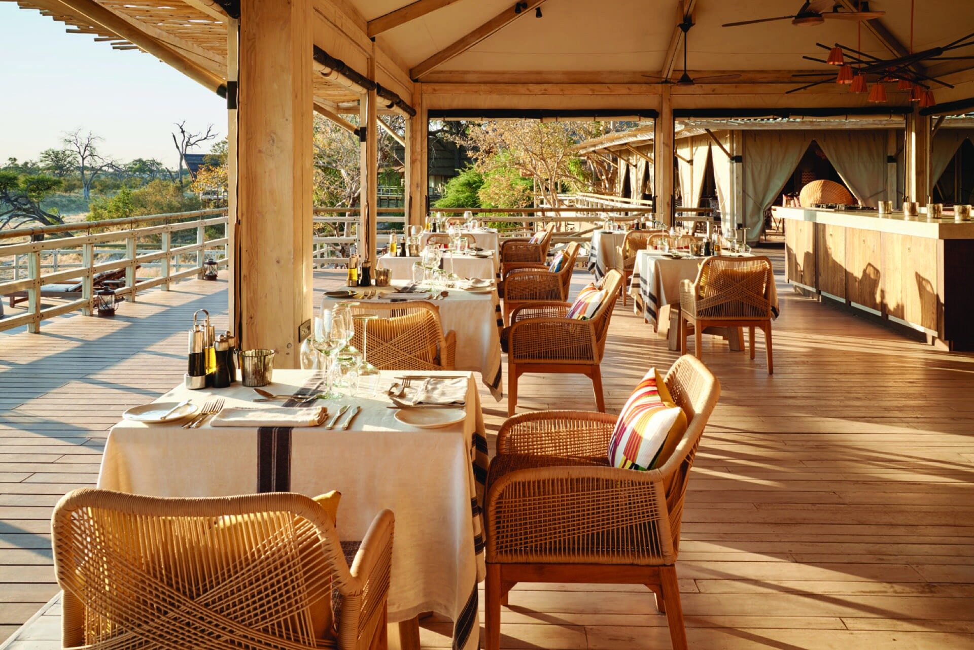 Small hosted group at a lodge deck, relaxed, sundowners