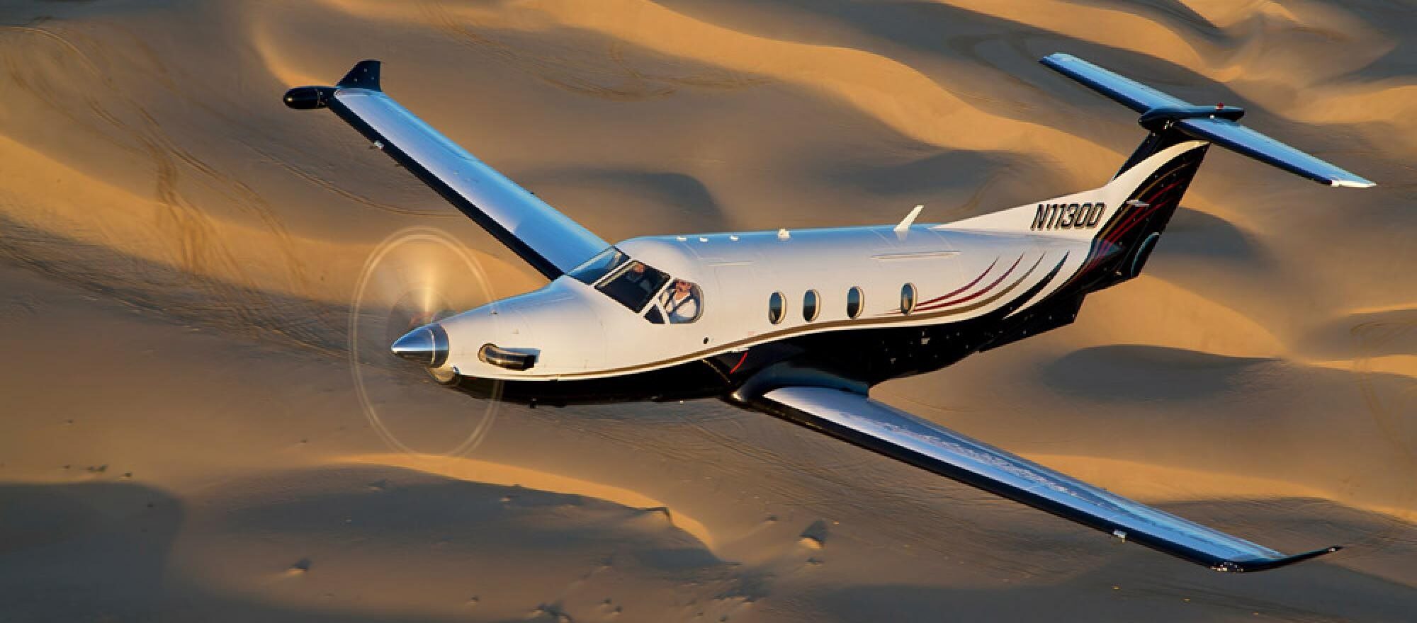 Pilatus PC-12 on a bush airstrip, golf travel bags being loaded, guests walking out